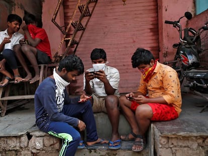 Um grupo de jovens checa seus celulares em Bombaim.