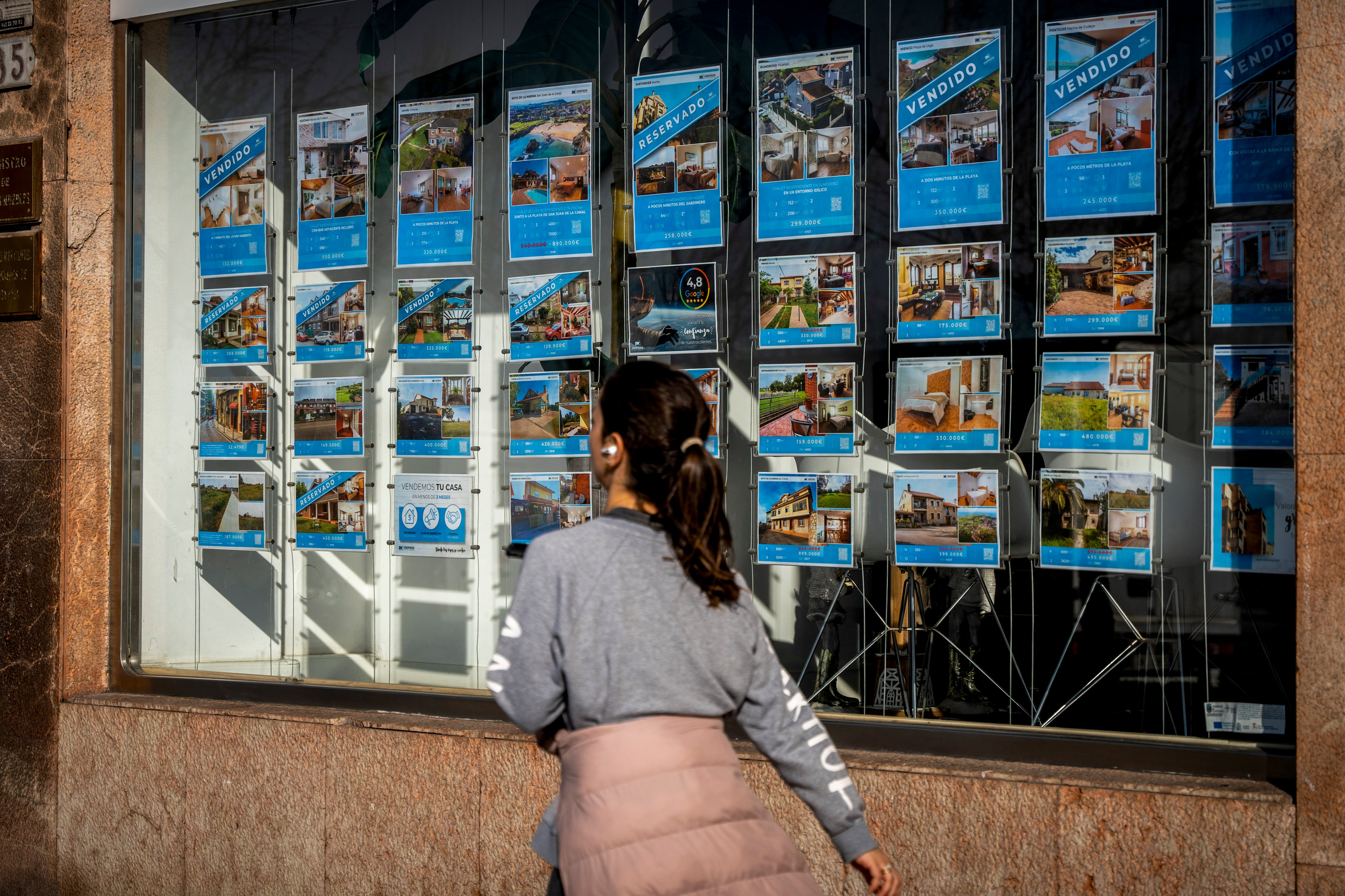 Una mujer pasa junto a una inmobiliaria en Santander.