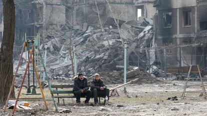 Dos vecinos de Mariupol en un banco delante de un edificio destruido por los bombardeos sobre la ciudad portuaria, el 25 de marzo.