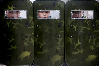 Tres niños se asoman por el cristal de sus escudos durante un entrenamiento en un campamento militar de verano situado en las afueras de Pekín (China), el 23 de agosto de 2013. Abrió sus puertas en 2008, cuando solo un puñado de estudiantes pasaron por allí. Ahora recibe más de 2.000 menores al año.