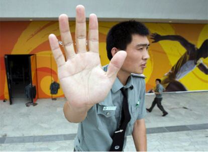 Un funcionario chino intenta evitar que le fotografíen delante de los barracones de la policía en el complejo olímpico.