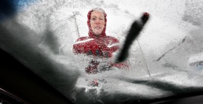 Una estudiante quita la nieve del parabrisas de su coche en Virginia.