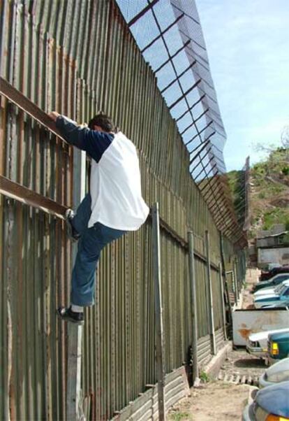 Un hombre intenta saltar la valla que separa México de EE UU.