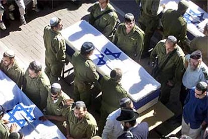 Guardias de seguridad de un asentamiento judío rinden honores a los colonos muertos.