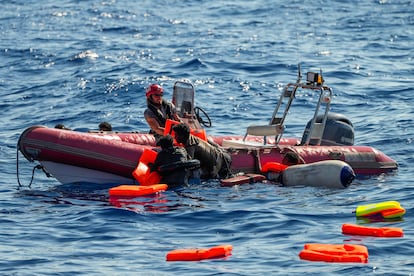 Un miembro de la tripulación del barco de Open Arms ayuda a los migrantes a subir a una lancha de rescate tras el naufragio de la patera.
