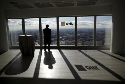 Un hombre mirando por una ventana del edificio de OHL en Madrid
