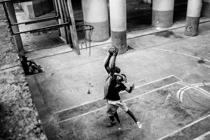 Un niño y un hombre juegan al baloncesto en la cancha que se encuentra en la planta baja de la torre.