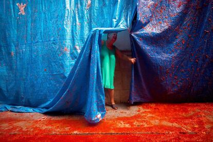 Una residente observa la calle bañada en pulpa de tomate durante la fiesta de la Tomatina, en Buñol (Comunidad Valenciana).