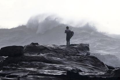 Un surfista observa el mar embravecido por el temporal de viento y lluvia en Avoca Beach, en la costa de Sidney, Australia.