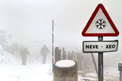 Dos personas suben a pie al albergue de los Ancares y Tres Obispos (Lugo) que permanece cubierto de nieve, el 18 de enero de 2015.