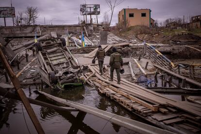 Soldados ucranios caminan sobre un puente destruido en Irpin, a las afueras de Kiev, este miércoles. El alcalde de la asediada Mariupol, Vadim Boichenko, ha denunciado este jueves el hallazgo de una nueva fosa común de unos 30 metros de extensión cavada por las tropas rusas a unos 20 kilómetros de la ciudad. Boichenko ha señalado que hay información de que “todos los crímenes ocurridos en la ciudad de Mariupol y que tienen signos de crímenes de guerra” están siendo ocultados por las tropas rusas en fosas comunes.