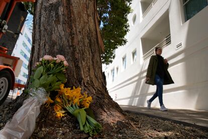 A woman walks past flowers left outside an apartment building where a technology executive was fatally stabbed in San Francisco