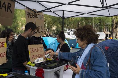 Una mujer colabora con la caja de resistencia de la acampada de plaza Universitat.