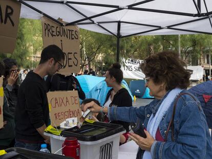 Una mujer colabora con la caja de resistencia de la acampada de plaza Universitat. 