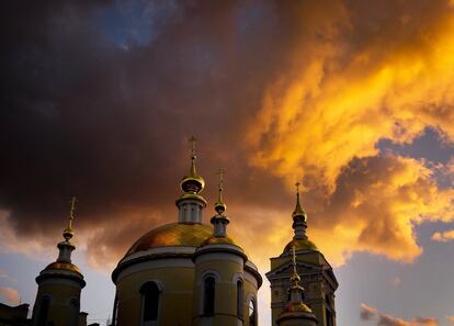 Nubes iluminadas por el sol durante el atardecer sobre una iglesia en Moscú (Rusia).