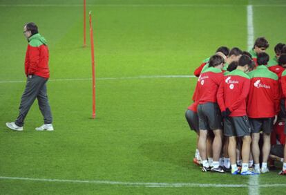 Bielsa reflexiona en el entrenemiento mientras los jugadores se agrupan.
