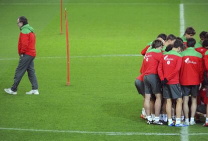 Bielsa reflexiona en el entrenemiento mientras los jugadores se agrupan.