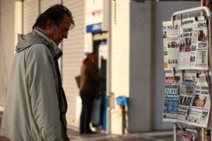 Un ciudadano lee los titulares de los principales periódicos griegos, en un kiosko de Atenas, Grecia. EFE/Archivo