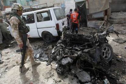 Un soldado, ante los restos de uno de los coche bomba que ha explotado hoy en Bagdad.