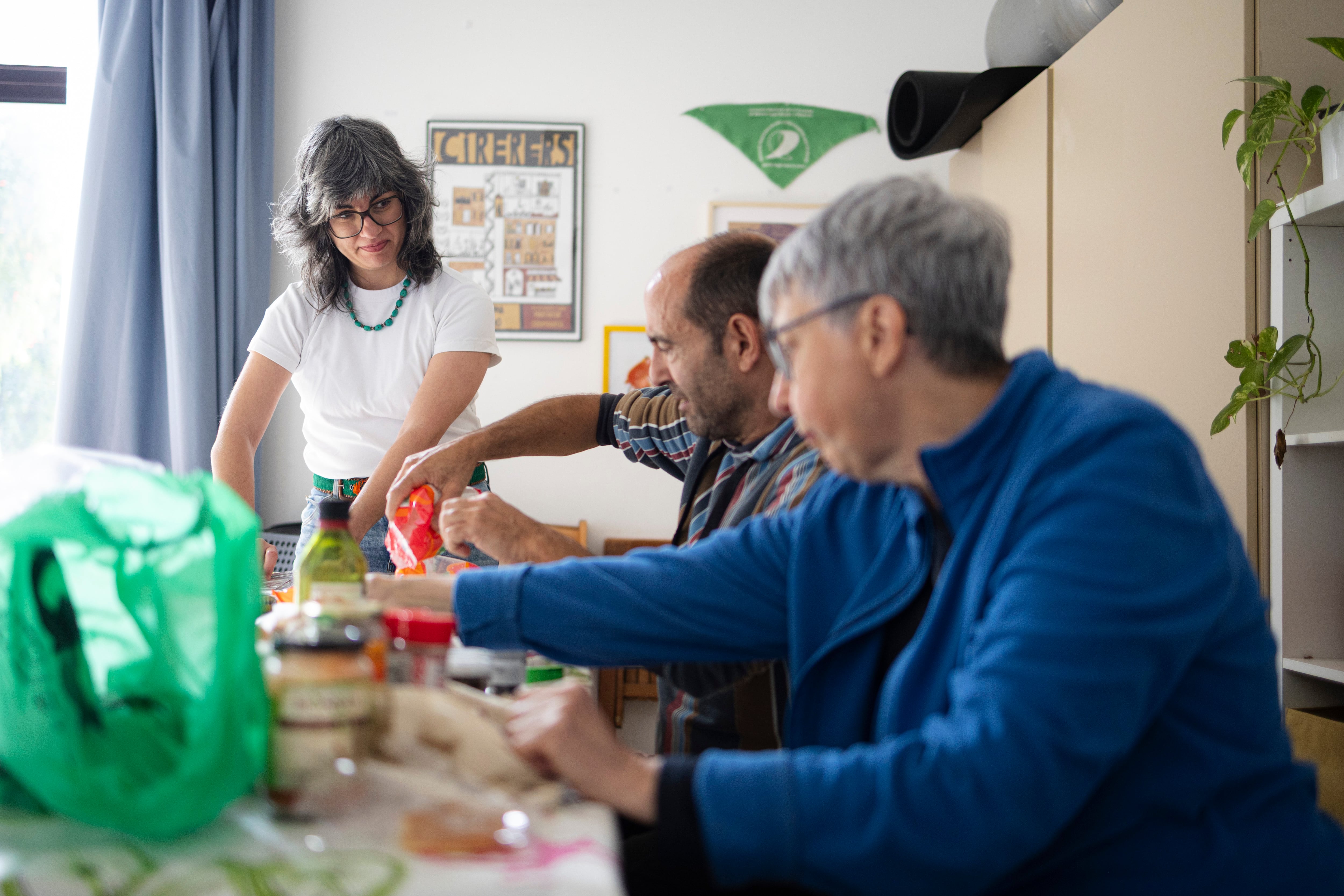 Ángela García (izquierda) comparte una comida con sus vecinos en la cooperativa Cirerers (Barcelona). 