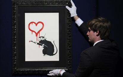 Un empleado de la casa de subastas Bonhams muestra a los medios la obra "Love Rat" del artista británico Banksy.