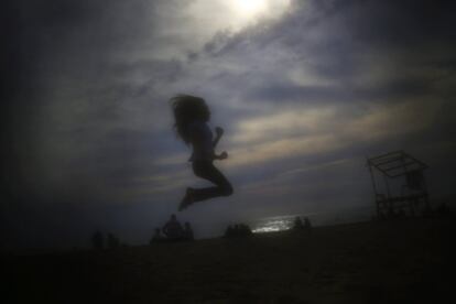 Una niña salta en la playa pública de Ramlet al Bayda en Beirut (Líbano). El velo impide que los demás vean las caras de las mujeres que llevan 'niqab'. El velo suele ir acompañado de ropas anchas que no solo cubren el cuerpo de la mujer también impide que se distingan sus formas.