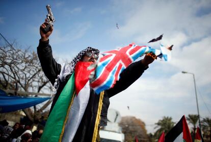 Un manifestante palestino sujeta una pistola mientras quema las banderas israelí y británica durante una protesta contra la decisión de Estados Unidos de recortar las ayudas en Gaza.