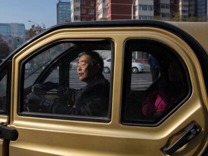 Un hombre conduce un pequeño coche eléctrico en Pekín.