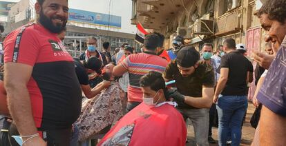 Barberos cortan el pelo y rasuran la barba a dos jóvenes, durante las concentraciones en la plaza Tahrir de Bagdad.