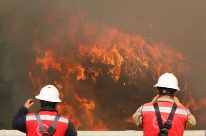 Un centenar de viviendas han ardido y unas 400 personas han sido evacuadas como consecuencia de un incendio declarado la tarde del lunes pasado que ha causado heridas leves a 19 personas, en su mayoría por inhalación de humo. En la imagen, una pareja de bomberos ante el incendio.