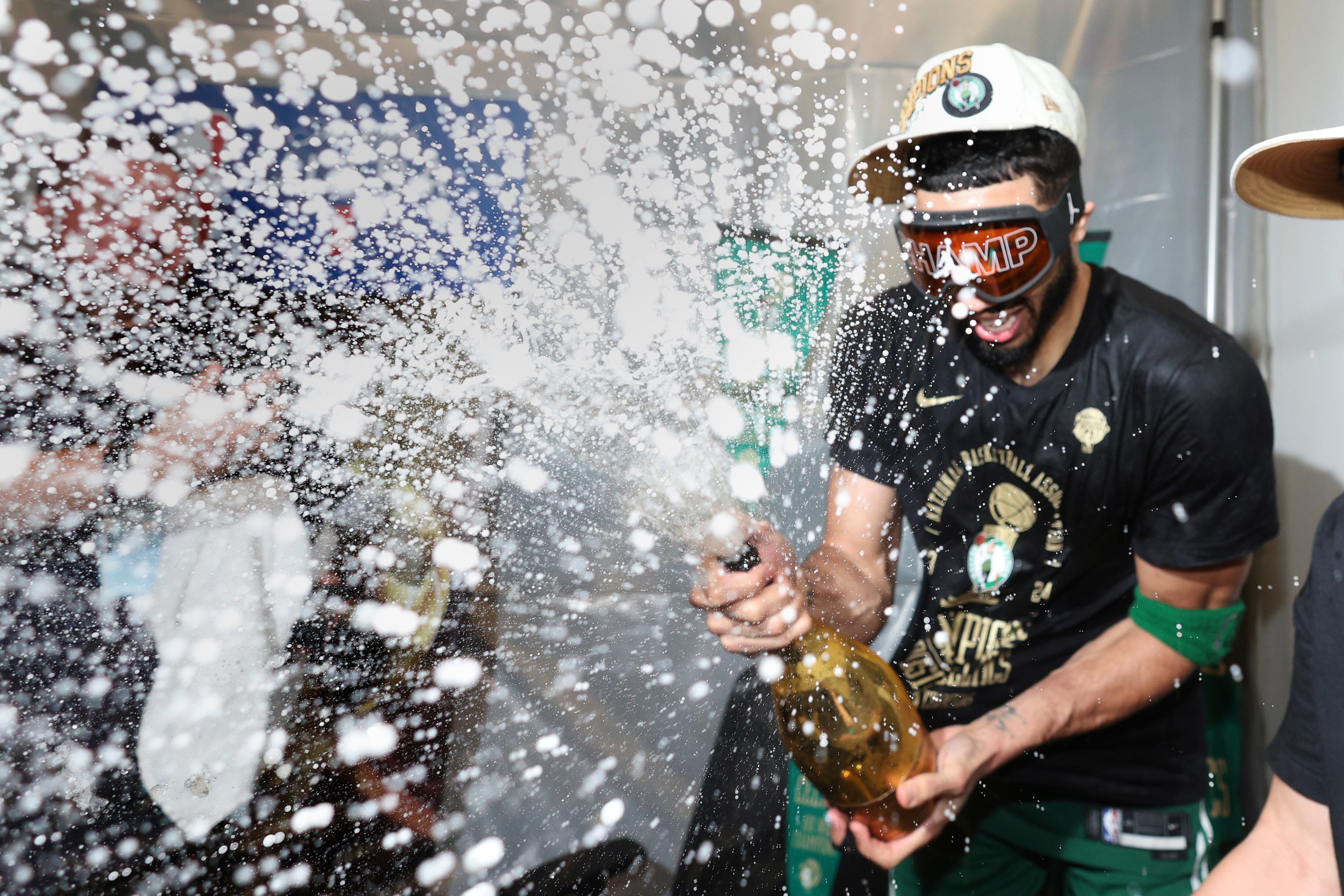 Jayson Tatum celebra con una botella de champán el triunfo de su equipo.