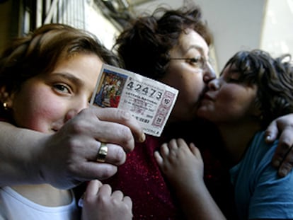 Una mujer y sus dos hijas se abrazan mientras muestran el décimo premiado con el 'gordo' en la Cervercería Asturias de Valencia.