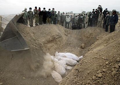 Una excavadora entierra los restos de víctimas del seísmo en una fosa común, ayer en Bam.