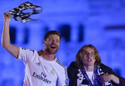 Xabi Alonso y Luka Modric saludan a los aficionados desde lo alto de la pasarela que rodea a la estatua de la diosa Cibeles.