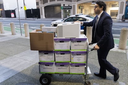 Un hombre porta los documentos para el juicio de accionistas contra Tesla y Elon Musk, junto al edificio Federal Phillip Burton y al Palacio de Justicia de EE UU en San Francisco, California.