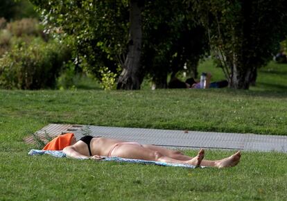 Una mujer tumbada en el césped de Madrid Río (Madrid).