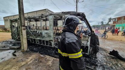 Un bombero este martes en Parnamirim, junto a los restos de un autobús incendiado en la ola de ataques a una veintena de ciudades de Rio Grande do Norte.