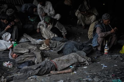El cuerpo de un drogadicto yace en el suelo mientras sus compañeros, casi ajenos a su muerte, siguen consumiendo droga debajo del puente de Pul-e-Sukhta de Kabul, en agosto. 