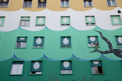 Una mujer mira por la ventana de un edificio decorado con murales de la artista italiana de la calle Iena Cruz y llamado 'Hunting Pollution', en Roma, 