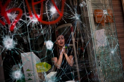 Mirian Burrueco, 30, reacts behind the broken glass of her store, which was attacked by protesters during clashes at the general strike in Barcelona, Thursday, March 29, 2012. 