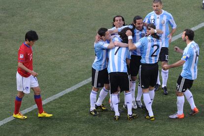 El mediocampista de Corea del Sur, Lee Chung Yong, camina cabizbajo mientras los jugadores argentinos celebran otro de los cuatro goles que han marcado a los argentinos.