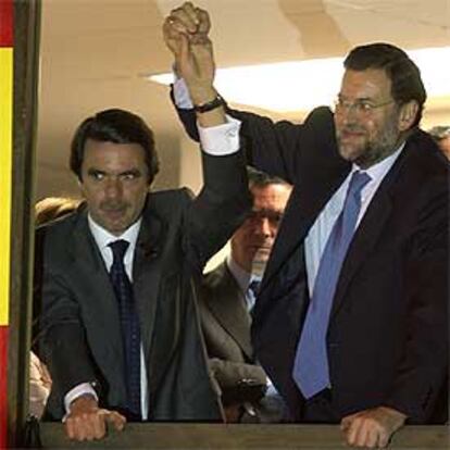 Rajoy alza la mano de Aznar en la ventana de la sede central del PP en Madrid la noche electoral.