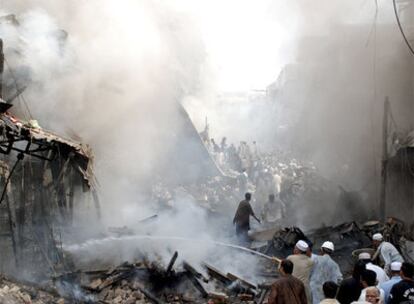 Un grupo de personas intenta extinguir el fuego  que siguió a la explosión del coche bomba en el mercado Meena de Peshawar.