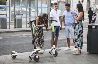 Varias personas observan los nuevos patinetes eléctricos de la empresa de alquiler Lime, en la plaza de Cibeles.