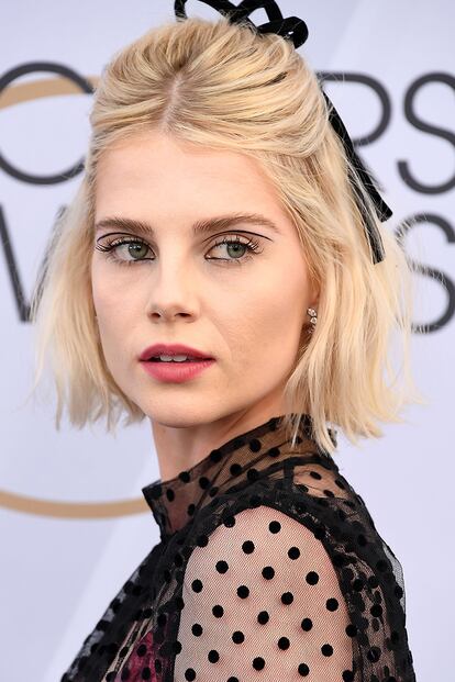 Lucy Boynton demuestra que el lazo no tiene por qué ser infantil. Una forma sencilla de darle un giro a un semirecogido con volumen y raya al medio. Llévalo también durante el día con un look desenfadado.