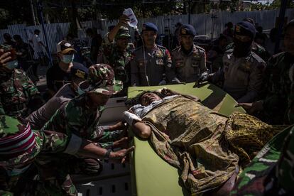 Policía y soldados indonesios evacúan una víctima de un hospital dañado, el 7 de agosto de 2018 en Tanjung.  