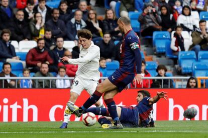 El lateral derecho del Real Madrid Álvaro Odriozola (a la izquierda) pelea un balón con el defensa del Eibar José Valdés 'Cote' (en el suelo) ante la mirada de Iván Ramis.