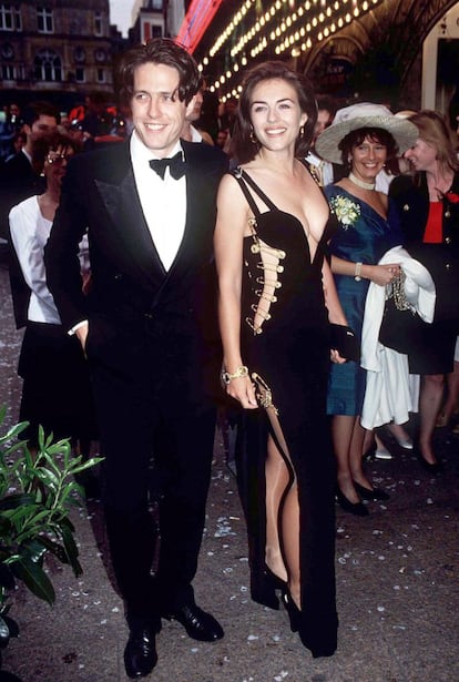 Nunca otra alfombra roja de Elizabeth Hurley ha dado tanto que hablar como la que pisó en 1994, con su entonces pareja Hugh Grant, en el estreno de 'Cuatro bodas y un funeral'. El vestido negro escotado y atado con imperdibles de Versace que lució la actriz acaparó todo el protagonismo de la 'premiere'. 