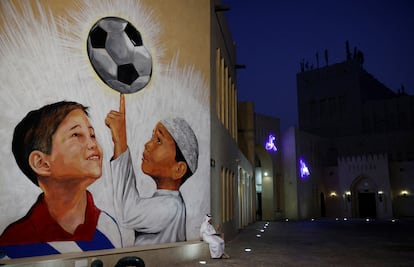 Un hombre sentado en un banco con un mural a la espalda en Doha, Qatar.