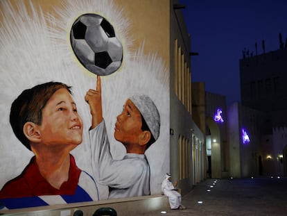 Un hombre sentado en un banco con un mural a la espalda en Doha, Qatar.
